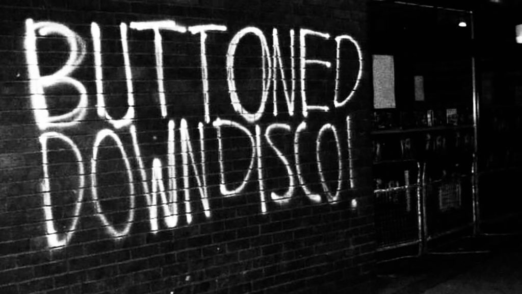 Buttoned Down Disco logo with white spray paint text on a black brick background