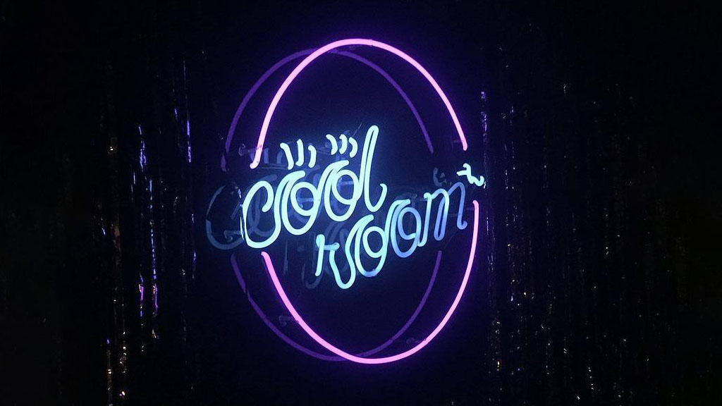 Cool Room logo with neon text in a circular design on a dark background